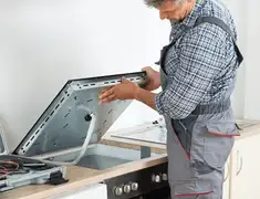 Appliance repair technician installing a built-in cooktop in Saint Louis, MO