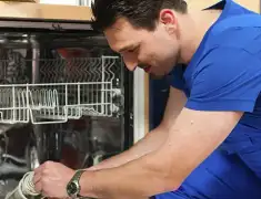 Dishwasher repair technician inspecting and servicing an open dishwasher in Saint Louis, MO
