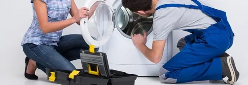 Washer repair technician inspecting a front-load washing machine with tools in Saint Louis, MO