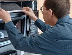 Appliance repair technician replacing a microwave vent filter in Saint Louis, MO