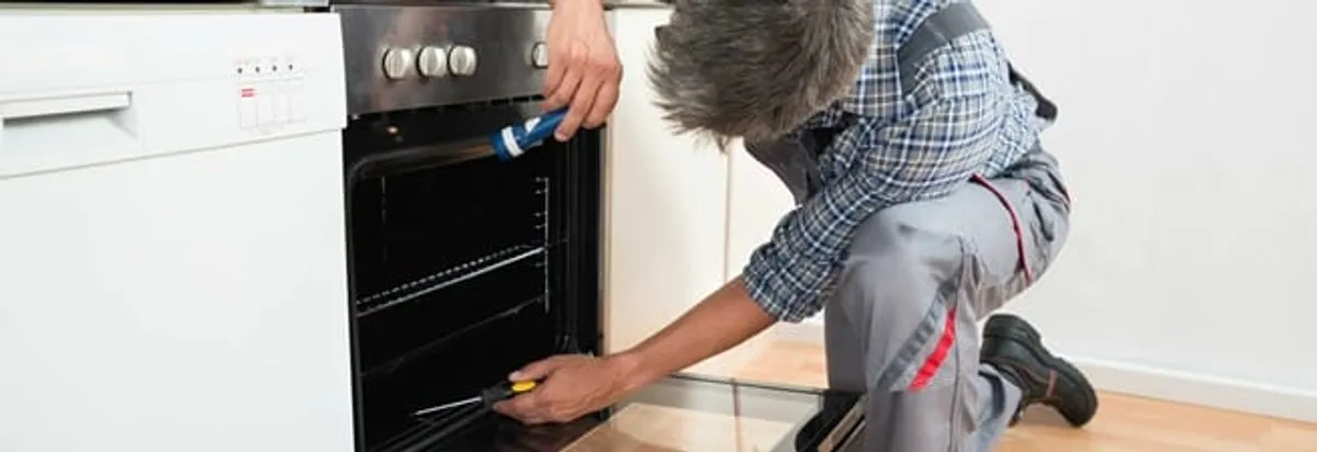 Oven repair technician inspecting and servicing an electric oven in Saint Louis, MO