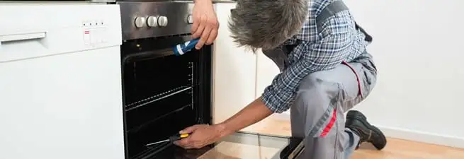 Oven repair technician inspecting and servicing an electric oven in Saint Louis, MO