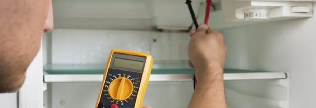 Refrigerator repair technician testing electrical components with a multimeter in Saint Louis, MO