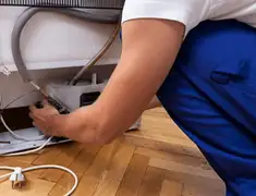 Appliance repair technician fixing refrigerator water line and connections in Saint Louis, MO