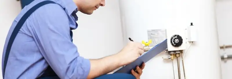 Water heater repair technician inspecting the unit and recording service notes in Saint Louis, MO